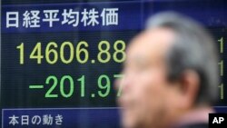 A man walks by an electronic stock price indicator showing the regional heavyweight, Tokyo's Nikkei 225, in Tokyo, April 8, 2014.