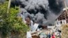 People are seen in front of clouds of black smoke from fires at the scene of an airstrike in Mekele, the capital of the Tigray region of northern Ethiopia, Oct. 20, 2021.