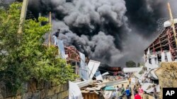 People are seen in front of clouds of black smoke from fires at the scene of an airstrike in Mekele, the capital of the Tigray region of northern Ethiopia, Oct. 20, 2021.