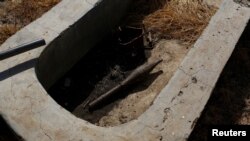 An unexploded rocket propelled grenade lies inside a cement water catchment in the village of Nialdhiu, northern South Sudan, Feb. 7, 2017.