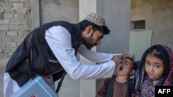An Afghan health worker administers polio vaccine drops to a child during a polio vaccination campaign in Kandahar on January 27, 2025.