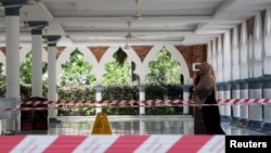 A woman wearing a protective mask walks at a mosque following the outbreak of coronavirus, in Kuala Lumpur, Malaysia, March 16, 2020. 