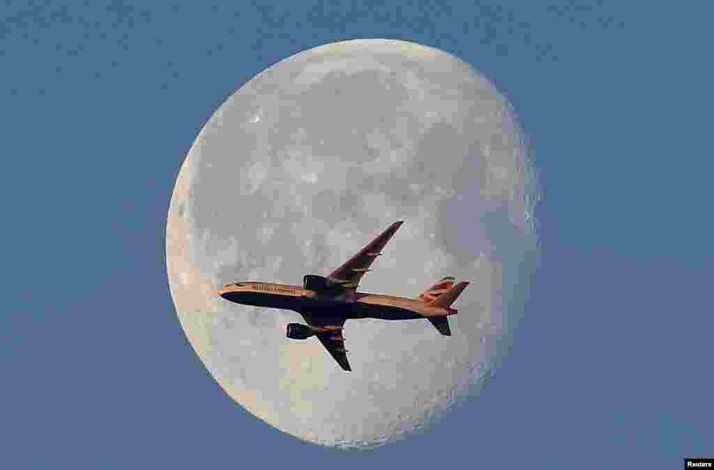 A British Airways passenger plane flies in front of the moon above London.