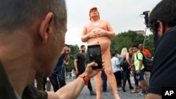 Orang-orang mengambil foto patung telanjang kandidat presiden AS Donald Trump di Union Square, New York (18/8). (AP/Mary Altaffer)