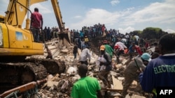 People look on as an excavator helps search for people trapped under debris after a landfill collapsed in Kampala, Uganda, on Aug. 10, 2024. Eight people were killed.