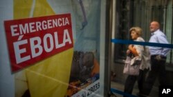 People walk by an advertising calling for financial help to fight Ebola in Africa in Madrid, Spain, Oct. 7, 2014.