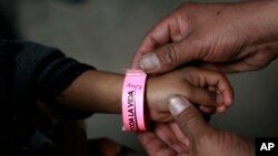 A child wears a bracelet marked with a number that indicates his place in line to submit his request for U.S. asylum, inside a shelter at Bachilleres gymnasium in Ciudad Juarez, Mexico, Feb. 19, 2019.