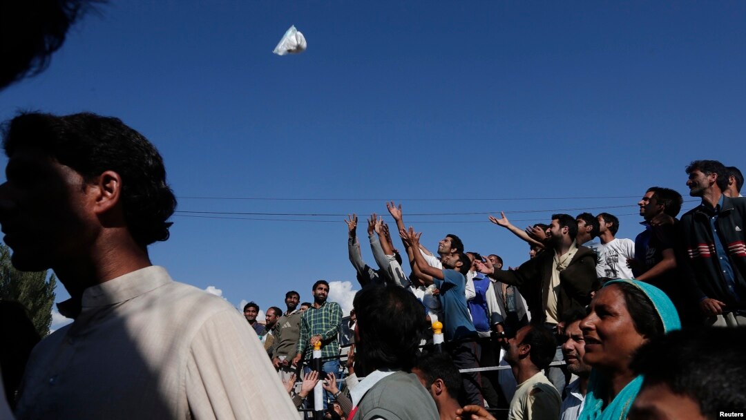 Flood victims try to catch relief material being given to them by Indian police personnel in Srinagar, Sept. 13, 2014. 