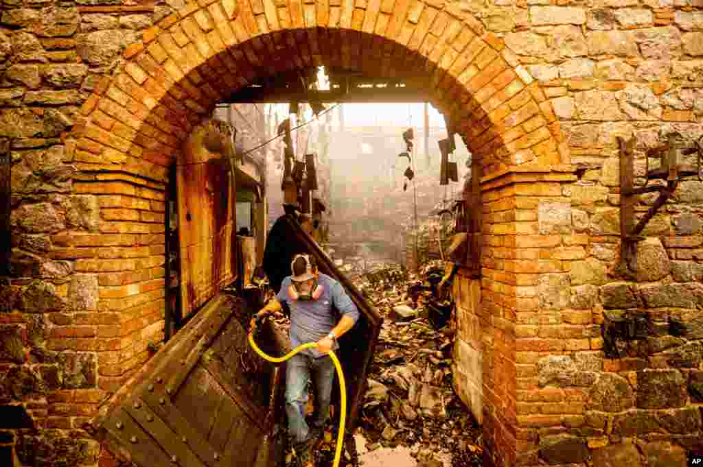 Cellar worker Jose Juan Perez extinguishes hotspots at Castello di Amorosa, Sept. 28, 2020, in Calistoga, California, which was damaged in the Glass Fire.