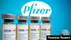 FILE PHOTO: Vials and medical syringe are seen in front of Pfizer logo in this illustration