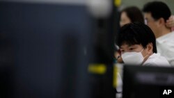 A currency trader wearing a face mask watches computer monitors at the foreign exchange dealing room in Seoul, South Korea, May 27, 2020. 