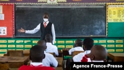 A teacher welcomes back students during a classroom lesson on day one of re-opening schools in Kampala, Uganda, Jan. 10, 2022.