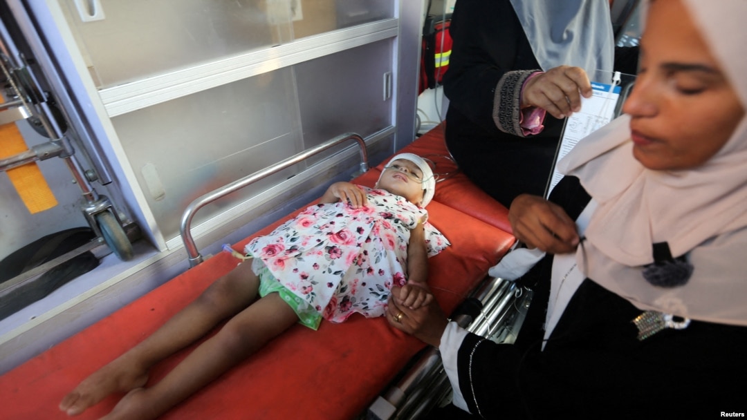 Seorang perempuan Palestina memegang tangan seorang anak pasien kanker, menunggu saat meninggalkan Gaza untuk berobat ke luar negeri, di tengah konflik Israel-Hamas, di Khan Younis, di Jalur Gaza selatan, 15 Agustus 2024. (Hatem Khaled/REUTERS)