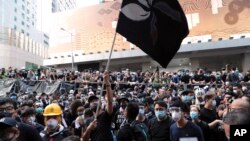 Para pendemo mengibarkan bendera Hong Kong yang dibuat berwarna hitam di depan markas kepolisian di Hong Kong, Jumat, 21 Juni 2019.