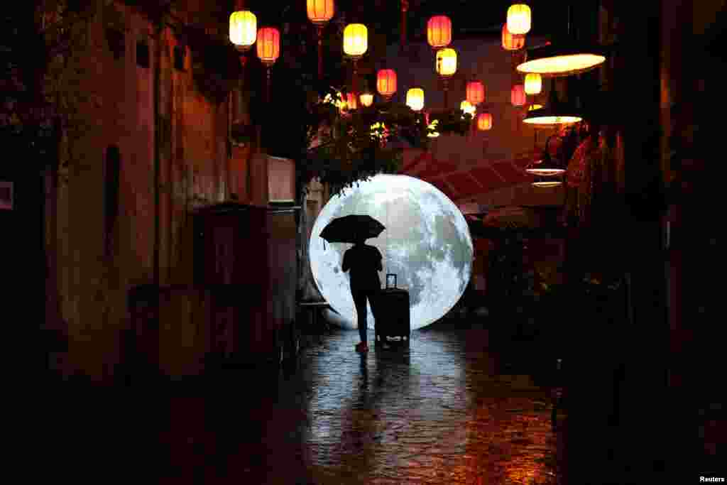 A tourist stands in front of a moon installation ahead of celebrations for the Mid-Autumn Festival at China Town in Kuala Lumpur, Malaysia, Aug. 24, 2019.