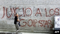 Una transeúnte pasa frente a una inscripción mural dirigida a los militares golpistas, en unas de las principales calles del centro de Caracas, el 15 de agosto de 2002. 