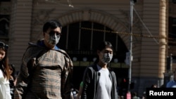 People wearing face masks walk by Flinders Street Station after cases of the coronavirus were confirmed in Melbourne, Victoria, Australia, Jan. 29, 2020.