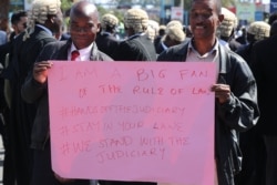 Protesters carry a sign during a demonstration against what they call government interference in the judiciary, in Blantyre, Malawi, June 17, 2020. (Lameck Masina/VOA)