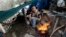 FILE - A man who goes by the name of D cooks lunch from a makeshift tent where he lives in the Jungle, a homeless encampment in San Jose, California, March 4, 2014.