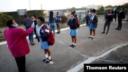 FILE - A teacher screens students for the coronavirus in Langa township in Cape Town, South Africa, June 8, 2020.