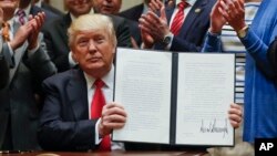 FILE - President Donald Trump holds up a signed executive order in the Roosevelt Room of the White House in Washington directing the Interior Department to begin a review of restrictive drilling policies for the outer continental shelf, April 28, 2017. 