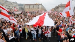 تظاهرکنندگان در مسیر میدان استقلال در مینسک پرچم بزرگ تاریخی بلاروس را حمل می‌کنند. ۲۳ اوت ۲۰۲۰