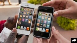 FILE - Noah Meloccaro, right, compares his older iPhone 4s to the new iPhone 5 held by Both Gatwech, outside the Apple Store in Omaha, Neb., Friday, Sept. 21, 2012 on the first day the iPhone 5 was offered for sale. 