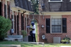 A mail carrier delivers mail at a home at the Dutch Village apartments, July 30, 2019, in Baltimore. The apartment complex is owned by Jared Kushner, son-in-law of President Donald Trump, who days earlier vilified Congressman Elijah Cummings.