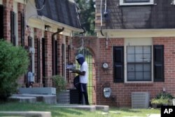 A mail carrier delivers mail at a home at the Dutch Village apartments, July 30, 2019, in Baltimore. The apartment complex is owned by Jared Kushner, son-in-law of President Donald Trump, who days earlier vilified Congressman Elijah Cummings.