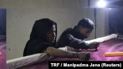 Mohammud Sanu and his wife work on fine needlework by the light of a solar lamp in Pipargaon Nevada village, in the Indian state of Uttar Pradesh, Jan. 9, 2018.