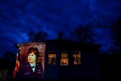 An image of veteran Constance 'Kandy' Pinard is projected onto the home she grew up in with her sister, Tammy Petrowicz, left, and brothers, Paul, center, and Brian Driscoll in Florence, Mass., May 14, 2020.