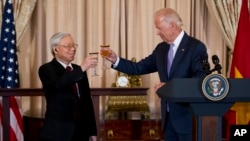 资料照片：2015年7月7日，时任美国副总统乔·拜登(右)与越南共产党总书记阮富仲在华盛顿国务院举行的欢迎午餐会上，共同举杯。（美联社照片）