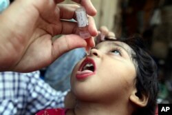 A health worker administers a polio vaccine to a child in Lahore, Pakistan, Monday, Aug. 22, 2022. (AP Photo/K.M. Chaudary)