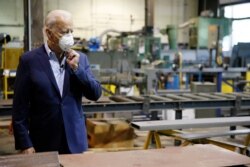 FILE - Democratic presidential candidate, former Vice President Joe Biden, adjusts his mask during a tour of McGregor Industries, a metal fabricating facility in Dunmore, Pennsylvania, July 9, 2020.