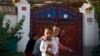 FILE - Uyghur children play while their relatives rest outside their house, decorated with Chinese lanterns and barbed wire at the Unity New Village in Hotan, in western China's Xinjiang region on Sept 20, 2018. 