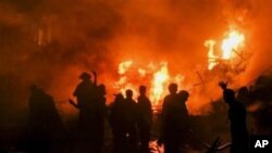 Pakistani firefighters struggle to extinguish fire at the site of a plane crash in Karachi, Pakistan, 28 Nov 2010