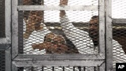 Leader of Egypt's Muslim Brotherhood Mohammed Badie, bottom center, and senior Brotherhood figure Salah Soltan, right, gesture during an appearance at a courtroom in Cairo, Egypt, April 1, 2014.