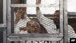 Leader of Egypt's Muslim Brotherhood Mohammed Badie, bottom center, and senior Brotherhood figure Salah Soltan, right, gesture during an appearance at a courtroom in Cairo, Egypt, April 1, 2014.