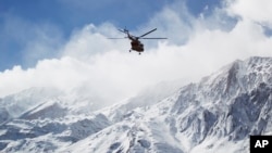 In this photo provided by Tasnim News Agency, a rescue helicopter flies over the Dena mountains while searching for wreckage of a plane in southern Iran, Feb. 19, 2018.