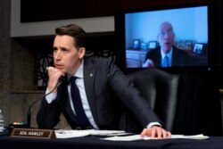 Sen. Josh Hawley, R-Mo., left, listens to former Sergeant-at-Arms Paul Irving testify via teleconference during a Senate Homeland Security and Governmental Affairs & Senate Rules and Administration joint hearing on Capitol Hill, Feb. 23, 2021.