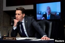 Sen. Josh Hawley, R-Mo., left, listens to former Sergeant-at-Arms Paul Irving testify via teleconference during a Senate Homeland Security and Governmental Affairs & Senate Rules and Administration joint hearing on Capitol Hill, Feb. 23, 2021.