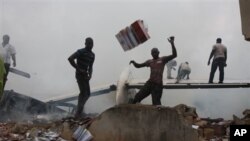 Wananchi wakirusha mabaki ya ndege ya Dana Airlines , katika eneo la makazi ya watu kaskazini mwa uwanja wa ndege wa kimataifa wa Murtala Muhammed Jumapili Juni 3, 2012.