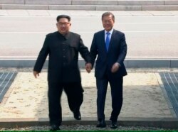 FILE - In this image taken from video provided by Korea Broadcasting System, April 27, 2018, North Korean leader Kim Jong Un crosses the border into South Korea, along with South Korean President Moon Jae-in for their historic face-to-face talks.