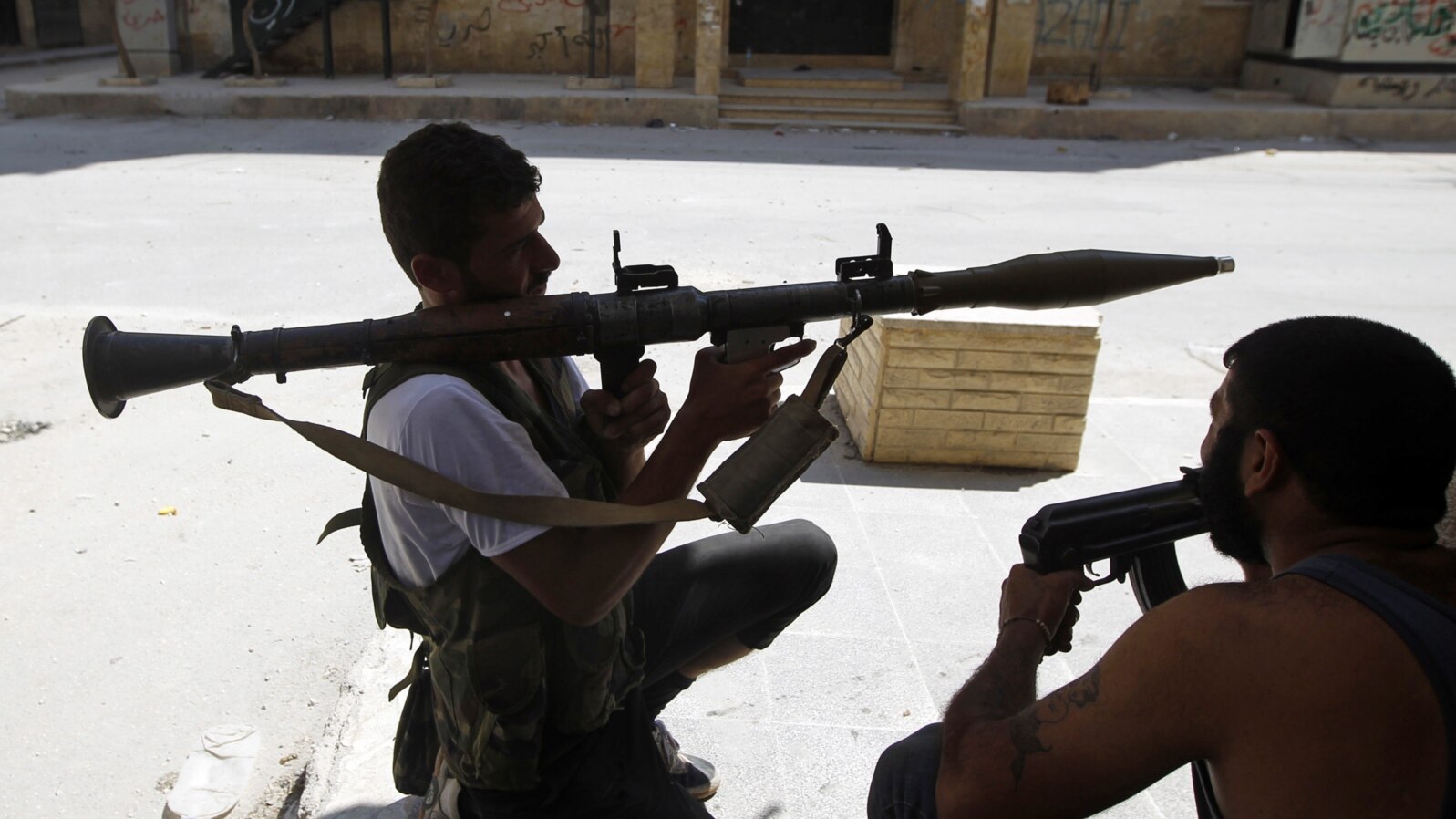 Free Syrian Army fighter waits for Syrian Army tanks to advance in the Salaheddin neighborhood in central Aleppo, Aug. 10, 2012.