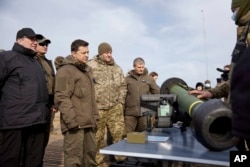 Presiden Ukraina Volodymyr Zelenskiy, kiri tengah, ditunjukkan senjata anti-tank NLAW selama latihan militer di luar kota Rivne, Ukraina utara, Rabu, 16 Februari 2022. (Kantor Pers Kepresidenan Ukraina via AP)