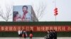 Men ride a scooter past a poster showing Chinese President Xi Jinping on the side of a school building in a newly developed part of Lankao County, Henan province, China February 22, 2019.