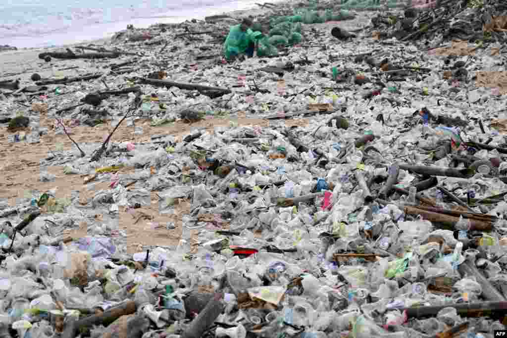 A man collects plastic and other debris washed ashore at a beach in Kedonganan, Badung Regency, on Indonesia&#39;s resort island of Bali.