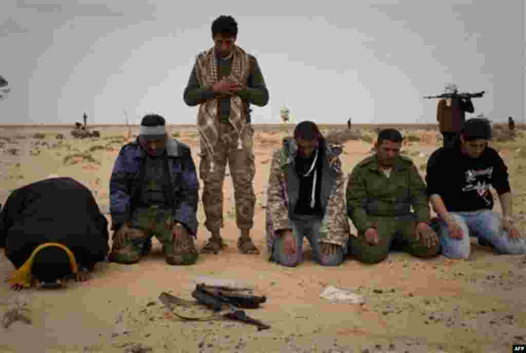 Libyan rebels pray in the desert on the frontline near Sultan, south of Benghazi, Libya, Friday, March 18, 2011. The U.N. Security Council voted Thursday to impose a no-fly zone over Libya and authorize "all necessary measures" to protect civilians from a