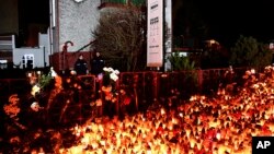 Lights, flowers and toys are left outside the escape room entertainment site where five teenage girls died in a fire last week, in Koszalin, northern Poland, Jan. 6, 2019.