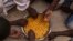 Migrants share a bowl of pasta during their lunch at the courtyard of a detention center for migrants, in the village of Karareem, around 50 kilometers from Misrata, Libya, Sept. 25, 2016. Libya is an important transit and destination country for migrants who arrive seeking employment or a path to Europe.